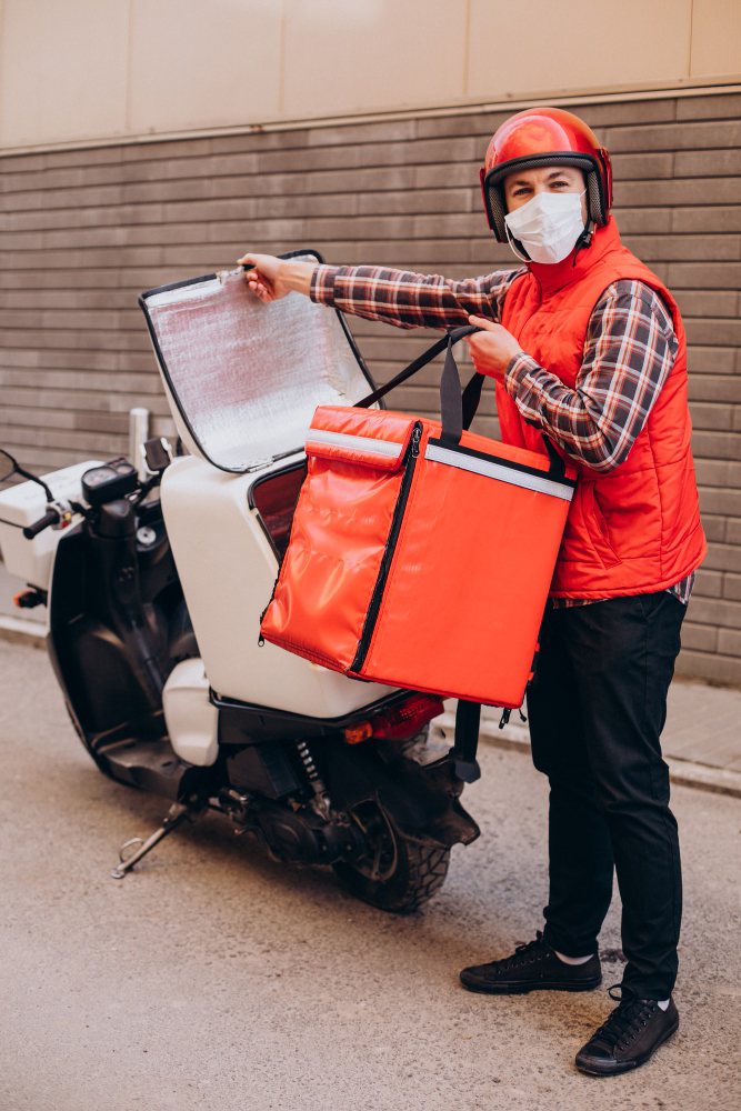Delivery driver with an insulated food bag by a scooter