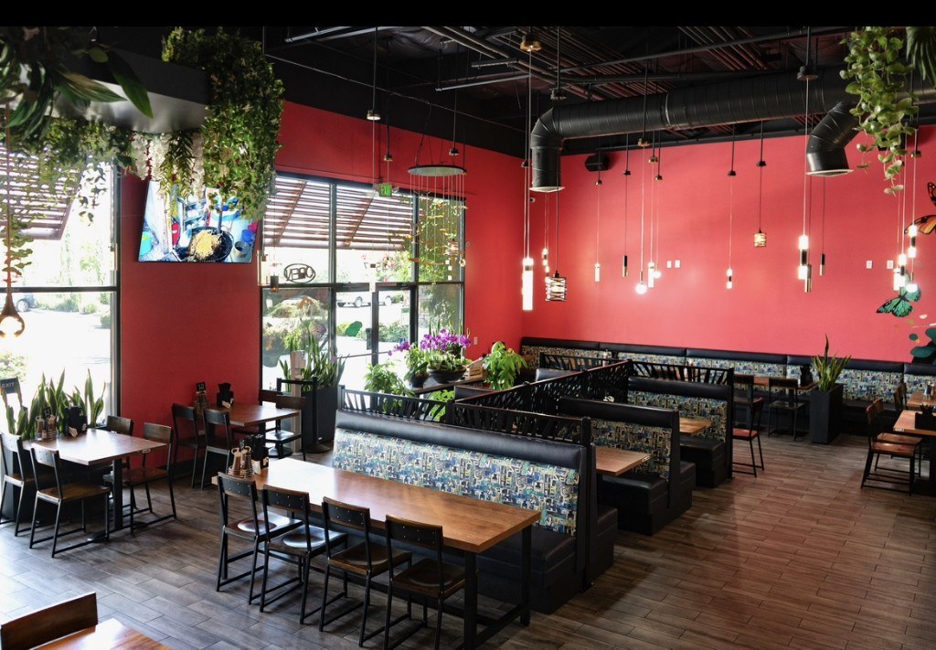 Dining room at Phở Ao Sen — family tables, booths, and the mural wall